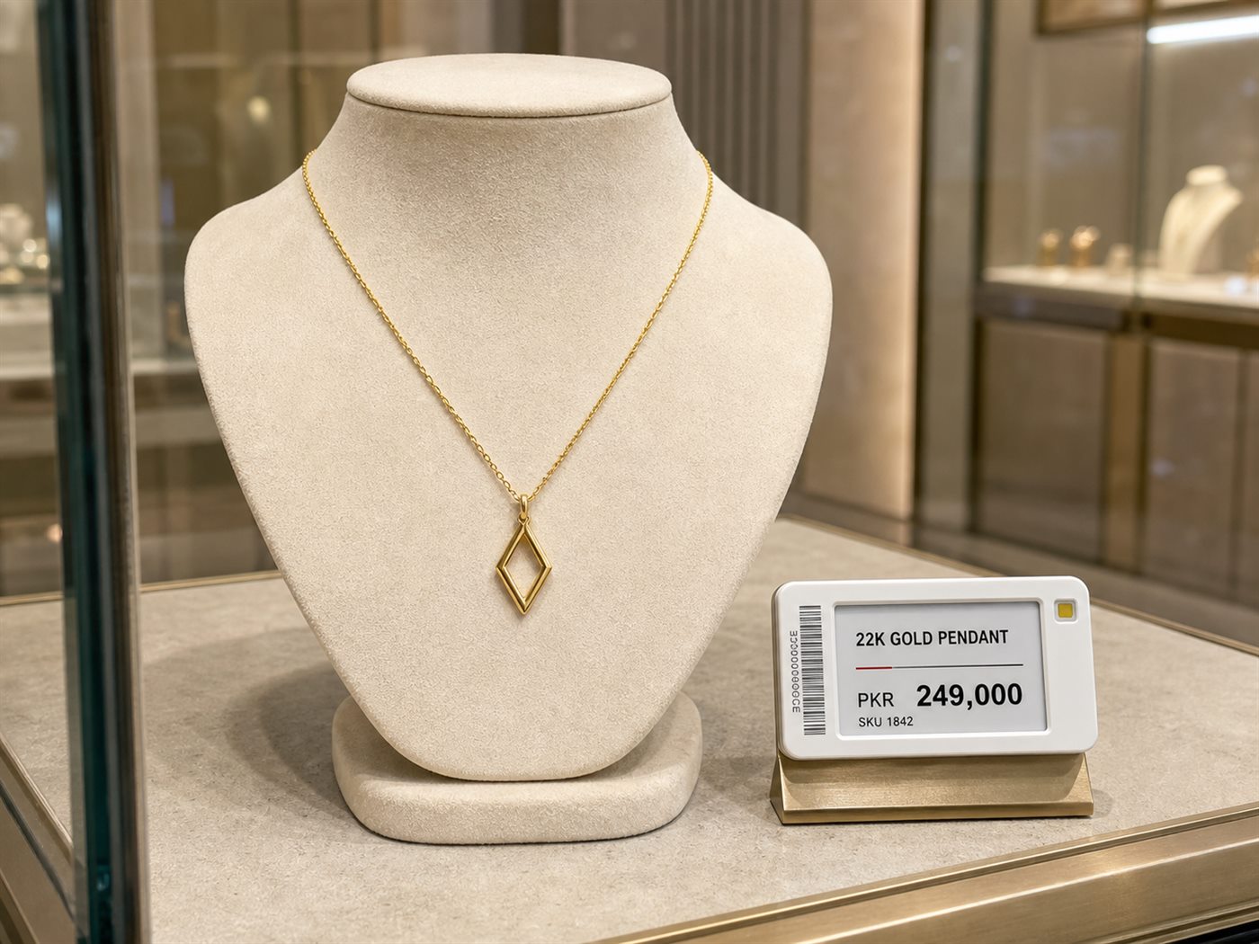 An electronic price label on a small stand beside a gold pendant necklace on a display bust.